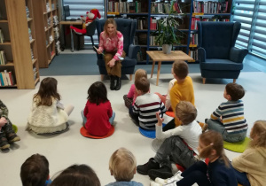 Dzieci słuchają bajki czytaną przez panią bibliotekarkę.